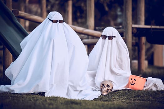 Halloween, glasses and people in ghost costume for trick or treat, global dress up day or fun on playground grass field. Fear fantasy, horror and relax friends role play scary phantom monster at park.