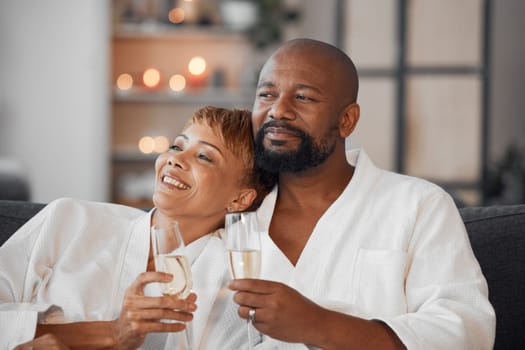 Spa, couple and romance with champagne relax, happy together and calm bonding on sofa. Married man, woman smile and relationship wellness therapy on romantic honeymoon or relaxing vacation travel.