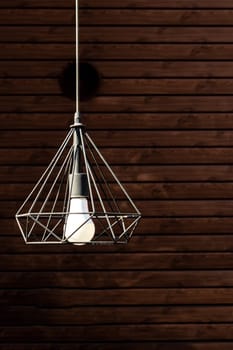 Modern garden pendant lamp hanging on the outdoor terrace during on wooden wall background, vertical.