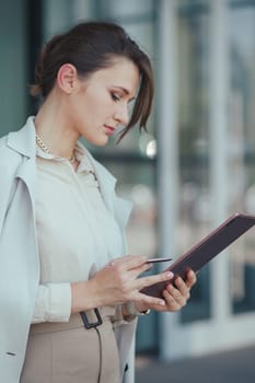 Business portrait of a young successful caucasian beautiful woman with a tablet in her hands, business technology concept, vertical.