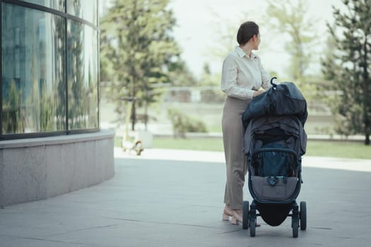 Business woman young mother with an empty baby stroller goes to work in the office building after sending the child to the nursery.