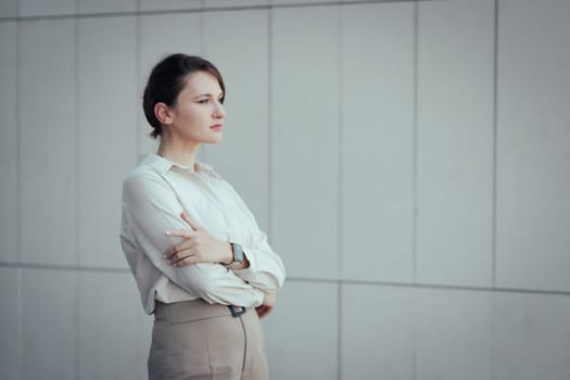 Portrait of young caucasian serious bisiness woman looking into the distance with crossed arms with copy space.