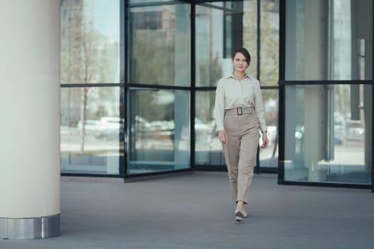 Caucasian attractive business woman in a business suit leaves the office building.