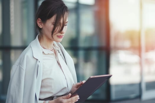 Young successful caucasian woman look at a tablet in her hands, business technology concept.