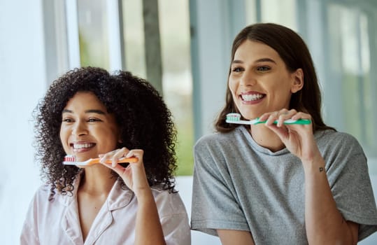 Toothbrush, oral care and women friends doing a dental, health and wellness morning routine together. Happy, smile and interracial females brushing their teeth for mouth hygiene in the bathroom