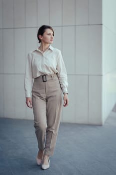 Young caucasian model woman in office or business fashion style pantsuit in beige tones, vertical.