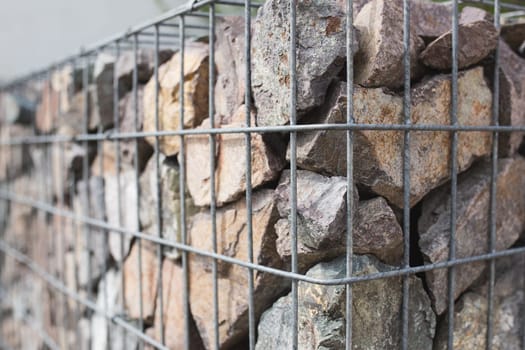 Close-up on a gabion mesh filled with stones installed in a garden.