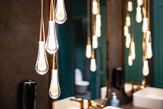 Hanging lighting in a luxury public bathroom with mirrors.