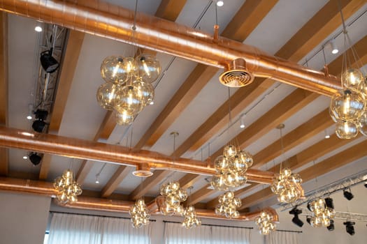 Ventilation system copper color, open type. Ceiling in a modern loft style with wooden beams, ventilation, trusses and lighting.