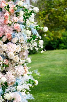 Luxurious flower decoration in the form of a column of roses, part of the wedding holiday decorations outdoor, vertical.