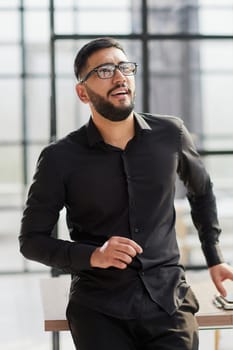 young businessman smiling in the office with his arms crossed