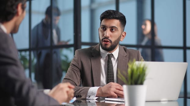 Two medium focused business workers communicate in the office.