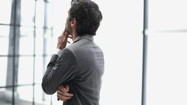 Young business man in profile view with hand on chin in office