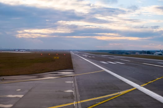 A long, straight runway stretches into the distance at the airport, with aircraft markings and clear paths for takeoff and landing