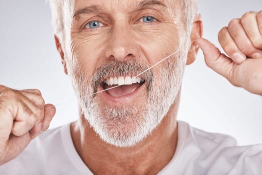 Dental, floss and face of senior man in studio isolated on a gray background. Portrait, cleaning or elderly male model with product flossing teeth for oral wellness, healthy gum hygiene or tooth care.