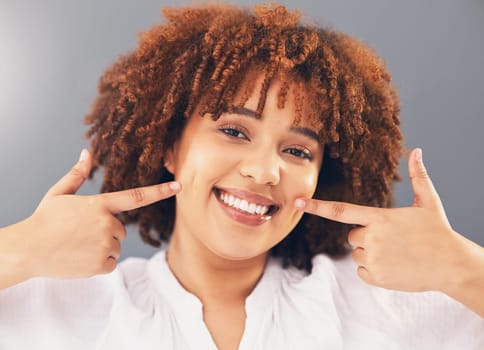 Portrait, point and teeth with black woman, smile or oral hygiene against grey studio background. Face, African American female or lady with gesture for mouth, happiness or dental health for wellness.