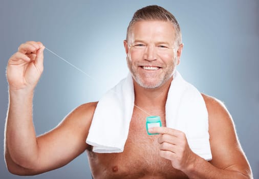 Dental, floss and portrait of man with product in studio isolated on a gray background. Oral hygiene, health and mature male model with container with thread for flossing, cleaning and teeth care