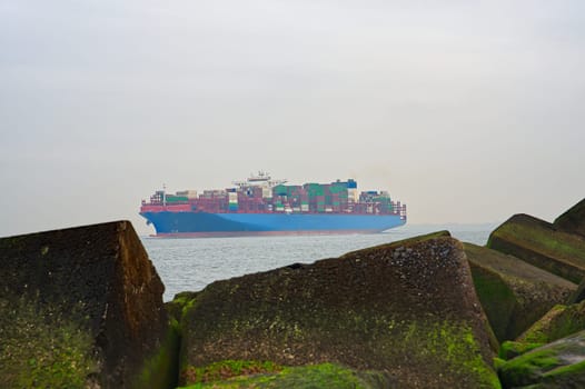 Large container ship leaves the port of Rotterdam. Cargo container ship in overcast day.