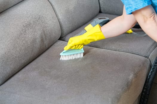Cleaning concept. Woman washes soft furniture in living room. Employee removing dirt from furniture, closeup