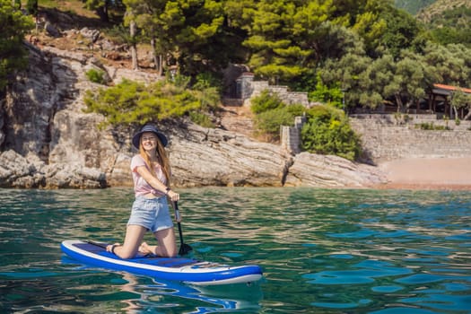 Young women Having Fun Stand Up Paddling in blue water sea near st stefan island against the backdrop of Milocer Park in Montenegro. SUP.