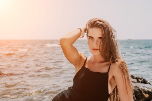 Woman travel sea. Young Happy woman in a long red dress posing on a beach near the sea on background of volcanic rocks, like in Iceland, sharing travel adventure journey