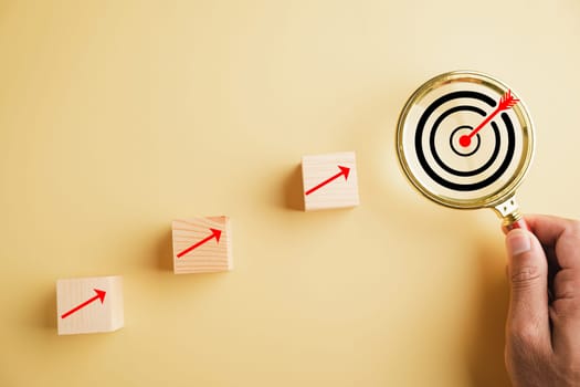 Target board is seen through magnifying glass, representing focused business objective, arrow points directly at the bullseye on dartboard, symbolizing search, goal, strategy, success in business