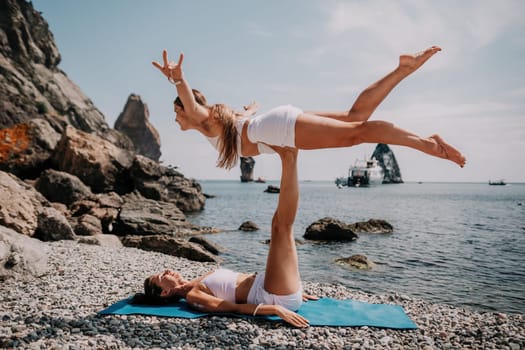 Woman sea yoga. Back view of free calm happy satisfied woman with long hair standing on top rock with yoga position against of sky by the sea. Healthy lifestyle outdoors in nature, fitness concept.