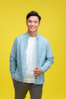 young pretty asian man posing in fashion style on light yellow background, lifestyle people concept