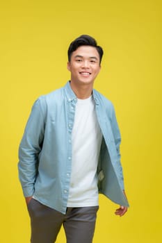 Funny young handsome man smiling on yellow background with copy space