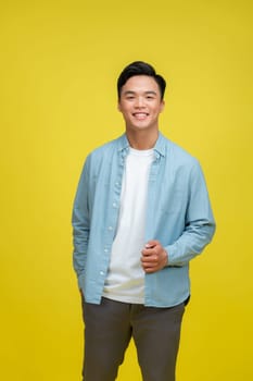 Young Asian man posing on yellow background