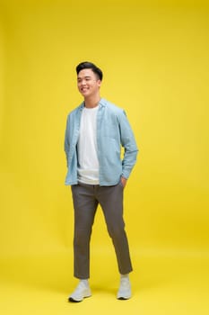 young pretty asian man posing in fashion style on light yellow background, lifestyle people concept