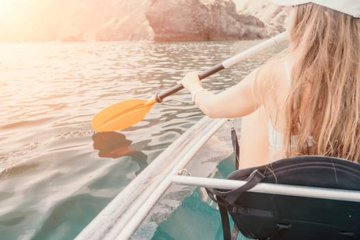 Woman in kayak back view. Happy young woman with long hair floating in transparent kayak on the crystal clear sea. Summer holiday vacation and cheerful female people having fun on the boat.