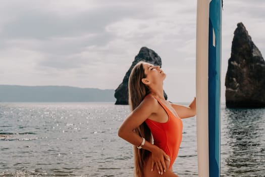 Close up shot of beautiful young caucasian woman with black hair and freckles looking at camera and smiling. Cute woman portrait in a pink bikini posing on a volcanic rock high above the sea