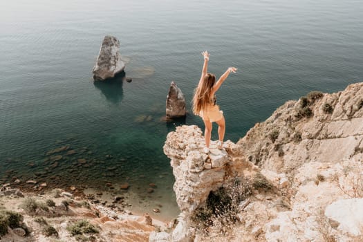 Woman travel sea. Happy tourist taking picture outdoors for memories. Woman traveler looks at the edge of the cliff on the sea bay of mountains, sharing travel adventure journey.