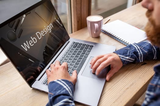 Cropped image of a young man working on his laptop in a coffee shop, rear view of business man hands busy using laptop at office desk, young male student texting on computer sitting at wooden table. Design. Web design