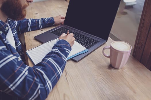 Cropped image of young man chatting via net-book during work break in coffee shop, male sitting in front open laptop computer with blank copy space screen for your text message or advertising content