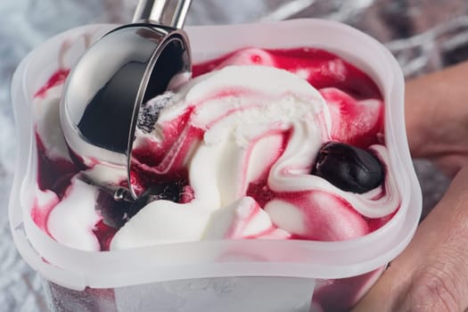 Cherry ice cream. An ice cream spoon is inserted into an ice cream with a cherry in a cup. Ice cream closeup. The concept of treats for children and adults. High quality photo
