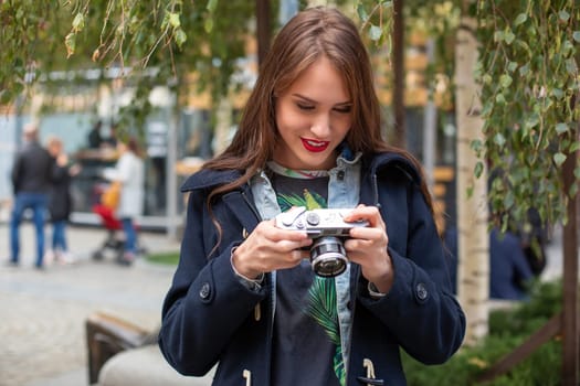 Portrait of a pretty young tourist taking photographs with vintage retro camera. Street style. Life style