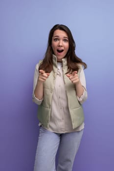 shocked brunette young lady in casual outfit on studio background.