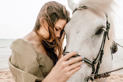 A woman in a dress stands next to a white horse on a beach, with the blue sky and sea in the background