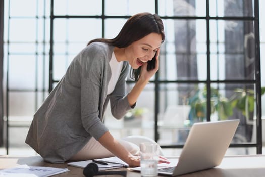 Businesswoman sitting in office, talking on the phone