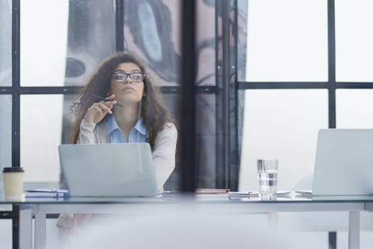Young businesswoman using laptop at table in office