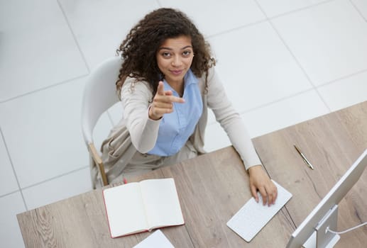 Image of young beautiful joyful woman smiling while working with laptop in office