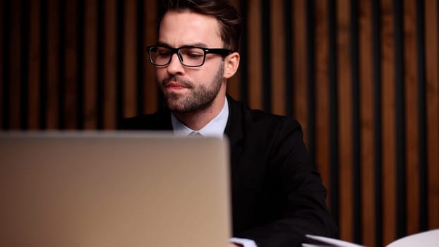 Shot of a young businessman using a computer at his desk in a modern office.