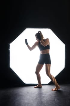 Female boxer training in a dark ring. Slow motion. Silhouette. Boxing concept