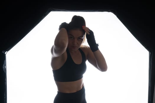 Female boxer training in a dark ring. Slow motion. Silhouette. Boxing concept