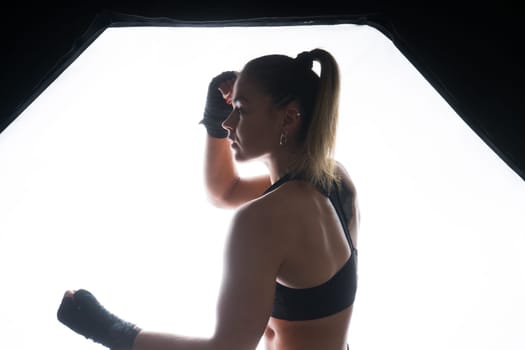 Female boxer training in a dark ring. Slow motion. Silhouette. Boxing concept