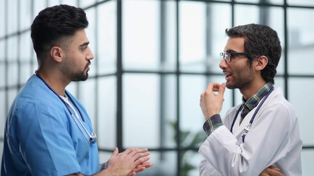Two doctors men having conversation and one of them has crossed arms