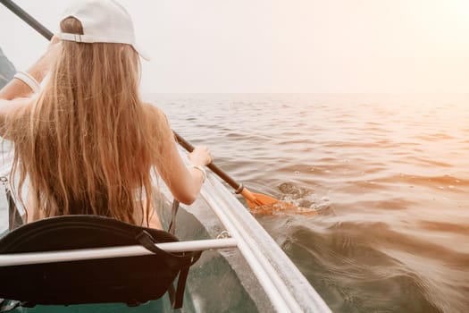 Woman in kayak back view. Happy young woman with long hair floating in transparent kayak on the crystal clear sea. Summer holiday vacation and cheerful female people having fun on the boat.