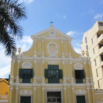 sky,tree,yellow,facade,building,cloud,symmetry,plant,window,architecture,church,house,landmark